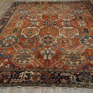 Large traditional rug with a rust-red field, patterned navy border, and detailed blue and beige medallions.