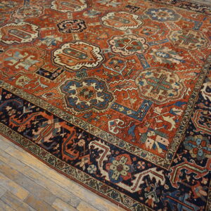 Rust and navy low-pile rug with geometric medallions rests on distressed wood planks.