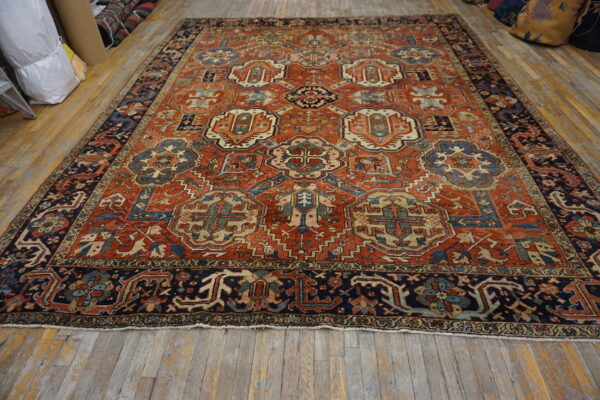 Rust and navy geometric rug with repeating medallions displayed on light wood flooring.