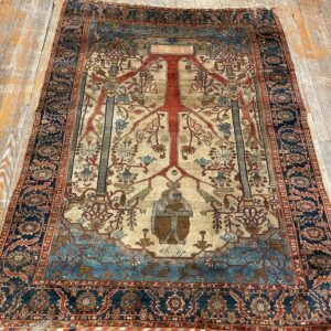 Navy, rust, and beige rug featuring a central Tree of Life motif and an anthropomorphic figure on wood flooring.
