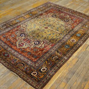 Ornate gold, red, and blue medallion rug displayed on rustic distressed wood floorboards.