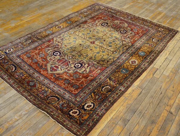 Ornate gold, red, and blue medallion rug displayed on rustic distressed wood floorboards.