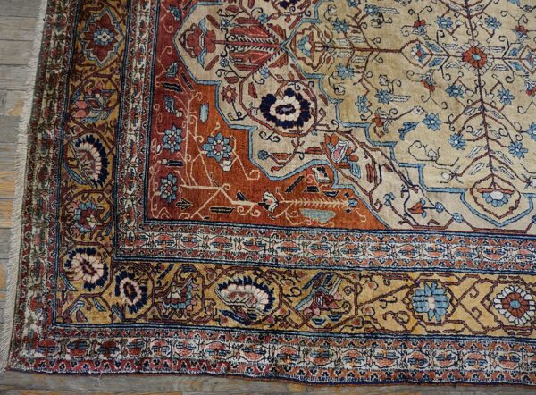 Detailed view of a low-pile rug featuring beige, rust, and blue floral patterns on gray wood flooring.