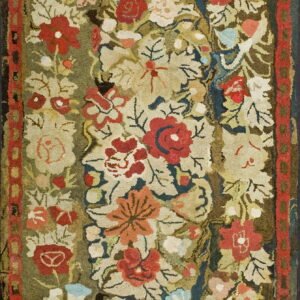 High-pile rug featuring a dense floral pattern in red, cream, and green with a geometric red border.