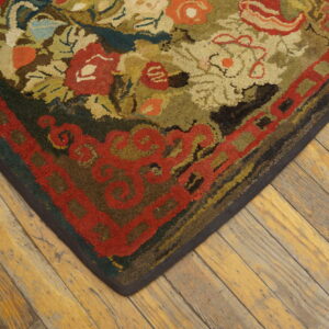 Textured floral rug in reds, greens, and beige rests on wide, distressed plank wood flooring.