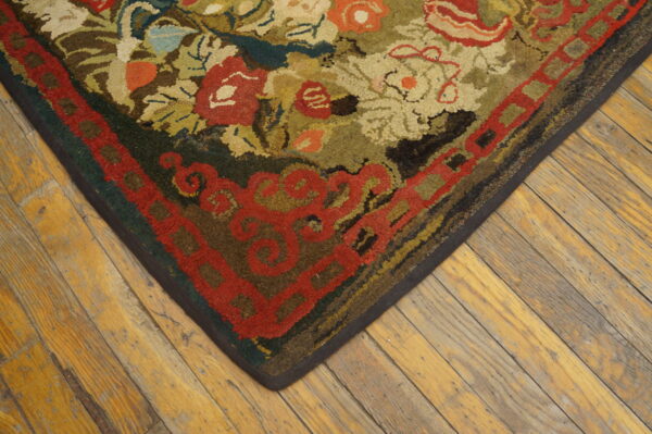 Textured floral rug in reds, greens, and beige rests on wide, distressed plank wood flooring.