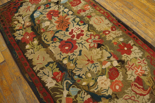 Muted floral rug featuring large red and orange blooms, green leaves, and a red border on wood planks.