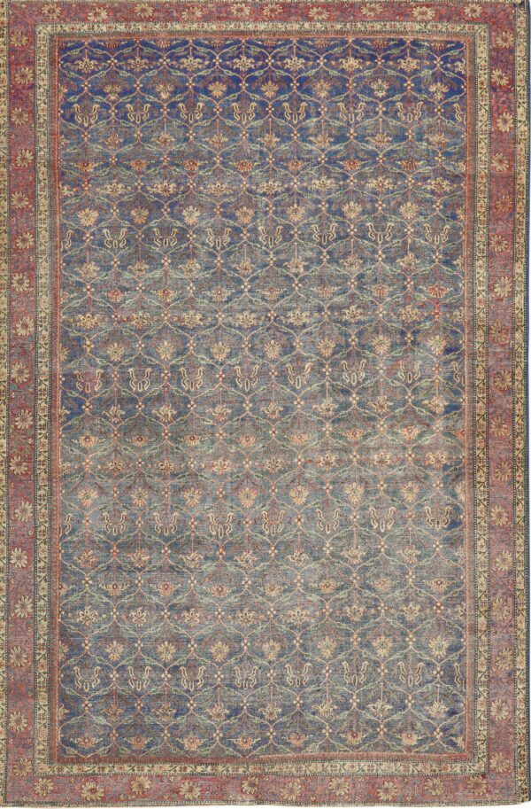 A deeply faded blue rug featuring an all-over distressed floral lattice and a wide rust red border.