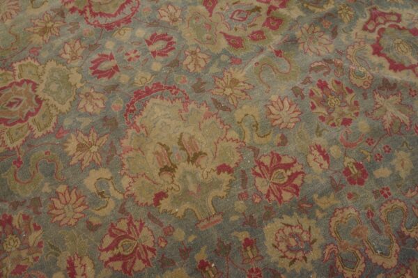 Low-pile rug with faded blue background and distressed rose and gold traditional floral patterns.