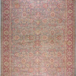 Rectangular area rug with an all-over intricate floral pattern in muted blue, rose, and beige.