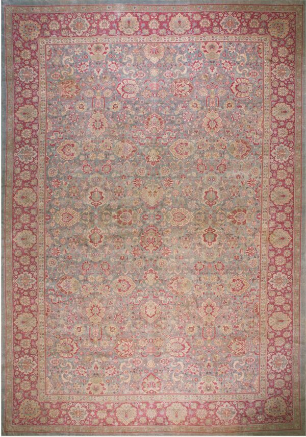 Rectangular area rug with an all-over intricate floral pattern in muted blue, rose, and beige.