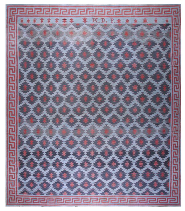 Flat-weave rug with blue and indigo geometric patterns, red accents, a greek key border, and the letters k. D. P.