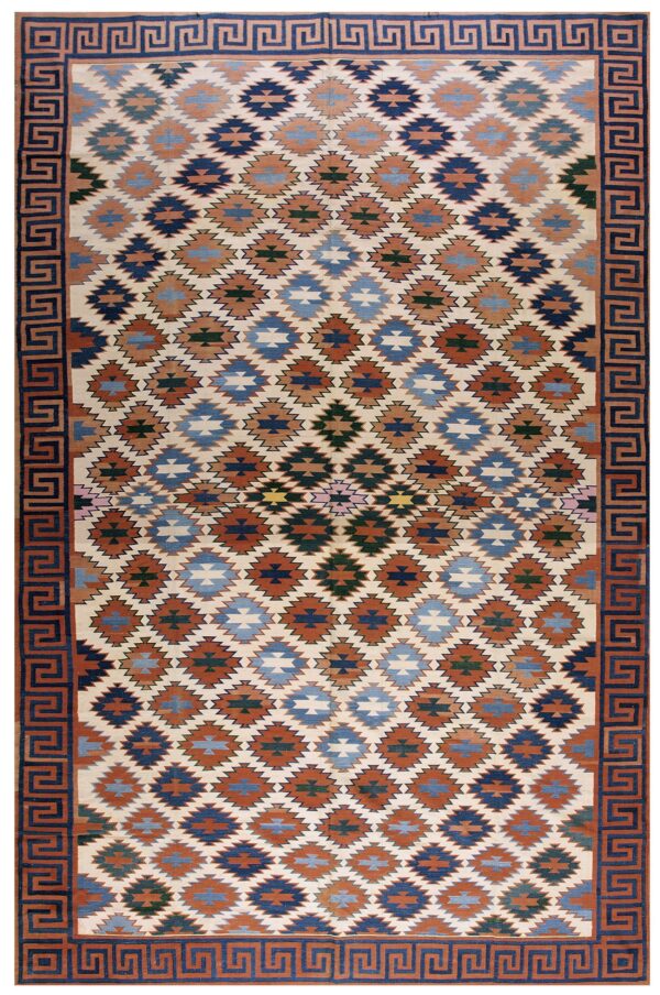 Flatwoven rug in cream, rust, and multi-blue geometric diamonds framed by a greek key border.