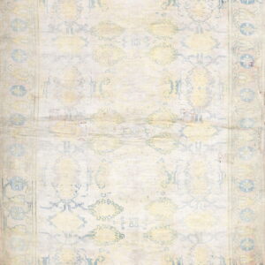 A highly washed rug featuring faint blue and yellow traditional designs on a cream background.