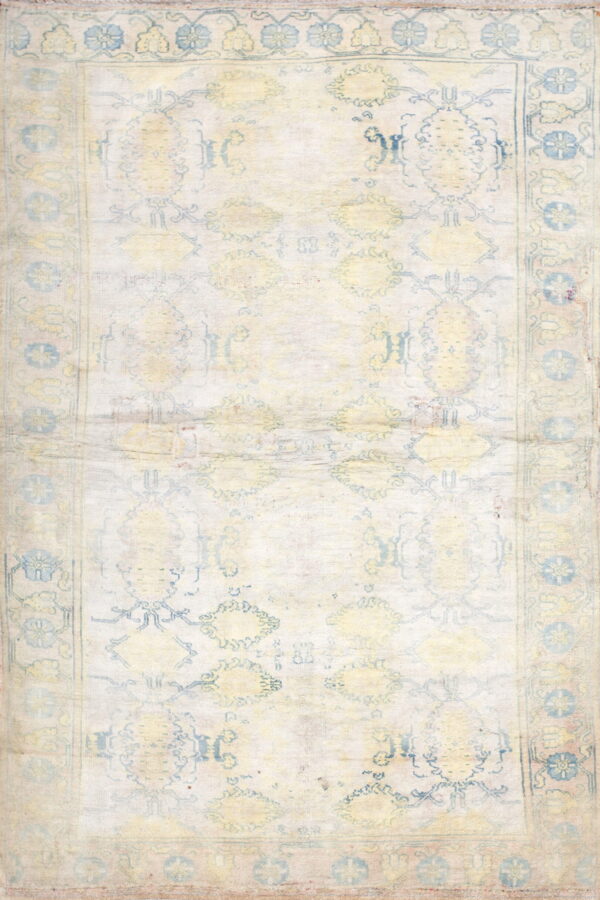 A highly washed rug featuring faint blue and yellow traditional designs on a cream background.