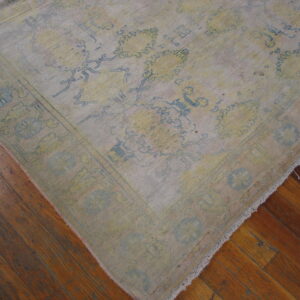Low-pile rug with distressed yellow and light blue floral designs on a glossy brown wood floor.