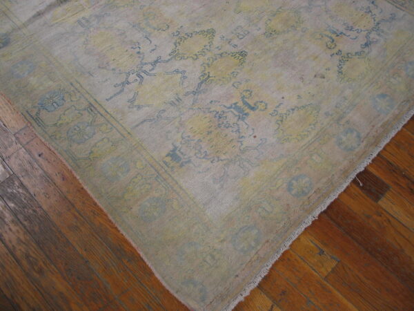 Low-pile rug with distressed yellow and light blue floral designs on a glossy brown wood floor.
