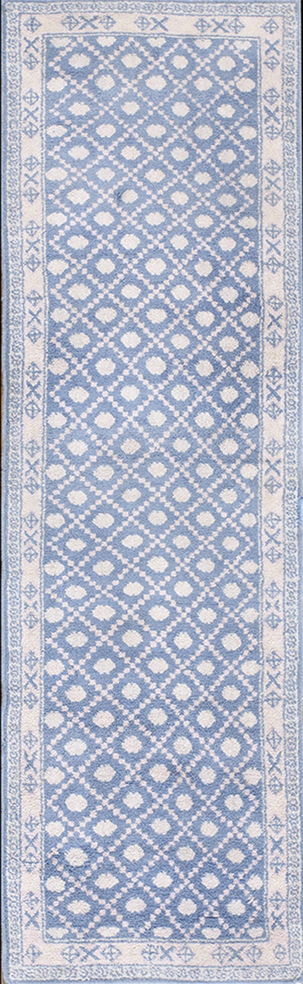 Blue runner rug with white repeating diamond pattern and a wide decorative geometric border.