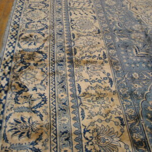 Navy blue and beige traditional floral patterned rug detail lying on light brown wood flooring.