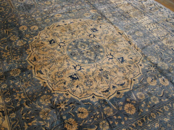 Muted blue and gold rug displaying a central circular medallion and complex floral border design.
