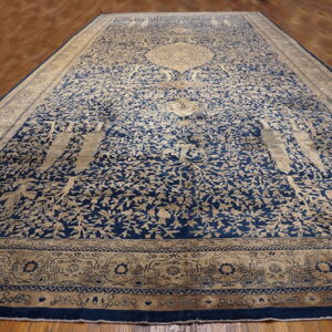 Large navy blue and beige rug with a detailed botanical pattern lying on polished hardwood flooring.