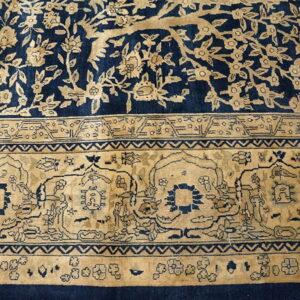 Navy blue and beige rug detail featuring a dense floral field and an elaborate arched primary border design.