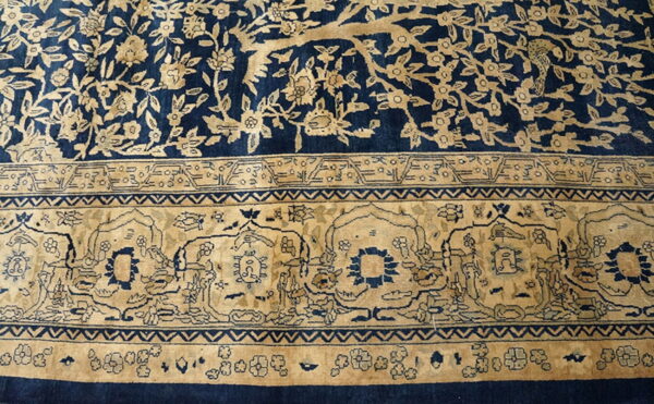 Navy blue and beige rug detail featuring a dense floral field and an elaborate arched primary border design.