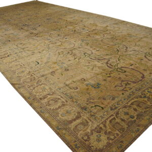 Muted gold and beige low-pile rug featuring a traditional ornate floral pattern and thick brown border.
