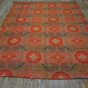 Orange, gold, and brown rug with an intricate octagonal and diamond medallion pattern on distressed wood flooring.