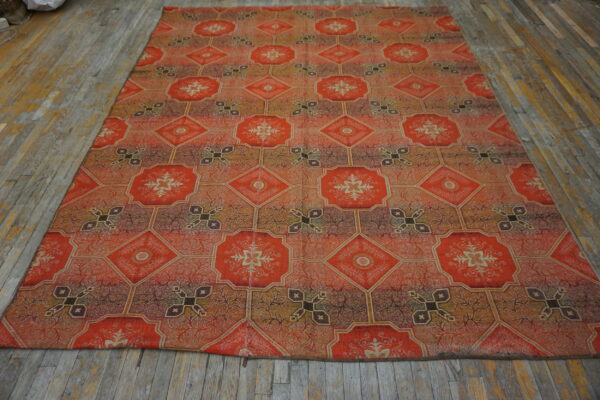 Orange, gold, and brown rug with an intricate octagonal and diamond medallion pattern on distressed wood flooring.