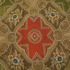 Close-up of an ornate, low-pile rug with a red medallion and floral scrolls in brown, olive green, and tan.