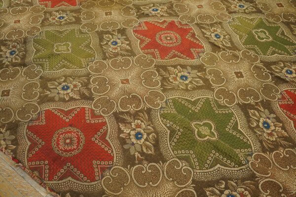 Woven rug with a complex pattern of red and green medallions on a brown scrollwork field.