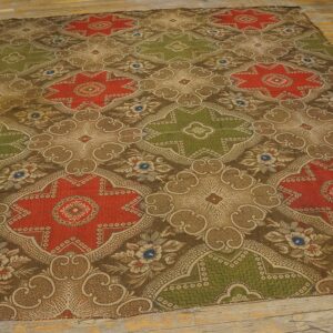Low-pile rug with alternating red and olive medallions over a detailed brown pattern on distressed wood planks.