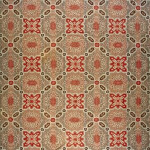 Low pile rug featuring repeating medallions and florals within a geometric lattice in red, taupe, and cream.