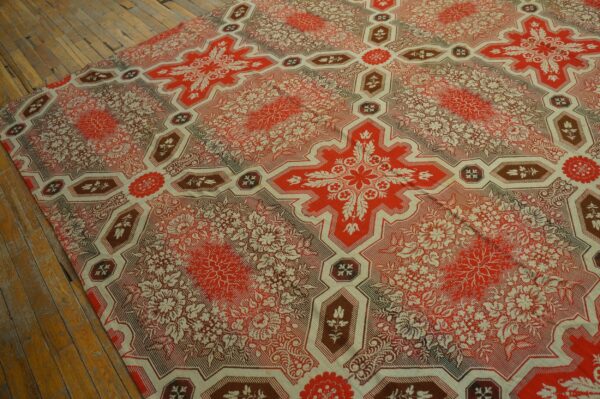 Red, cream, and brown rug featuring large geometric floral crosses covers worn wooden planks.