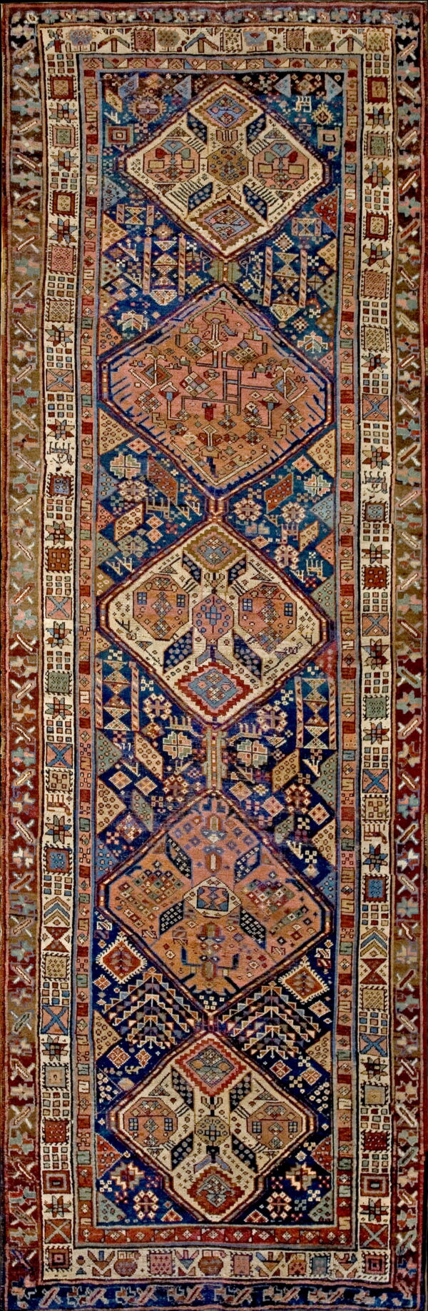 Full view of a runner showing repeating rust and cream geometric medallions on a dark blue ground.