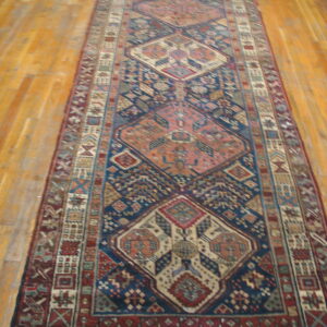 Runner rug with large geometric medallions in navy blue, rust, and tan on wood floors.