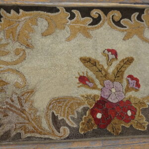 Ornate high-low pile rug featuring gold scrollwork, a beige center, and red-and-purple floral accents on wood flooring.