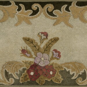 Beige hooked rug with a central red and mauve floral arrangement and scrolling gold leaf borders.
