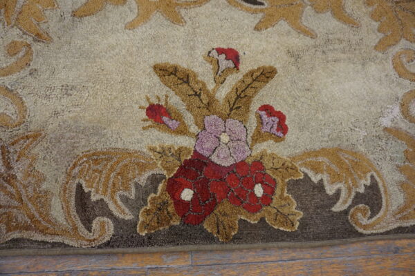 High-pile rug featuring red and purple floral patterns with tan leaves on a cream background over wood flooring.