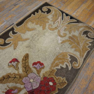 Highly textured floral rug in cream, tan, and red, placed on worn wooden plank flooring.