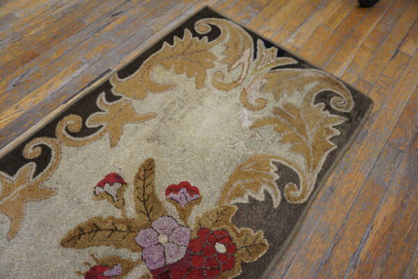 Highly textured floral rug in cream, tan, and red, placed on worn wooden plank flooring.