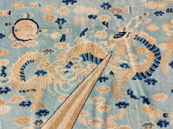 Light blue rug detail featuring a golden dragon design surrounded by cream, gray, and dark blue clouds.
