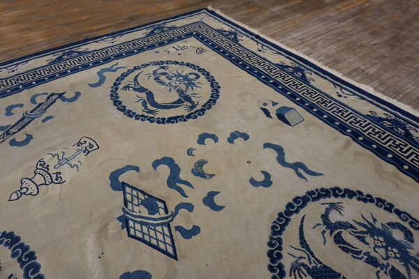 Blue dragon and symbolic motifs on a beige rug field laid upon worn wood flooring.