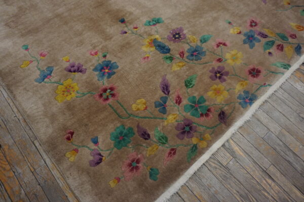 High-pile taupe rug with a winding multi-colored floral design rests on distressed gray wood flooring.