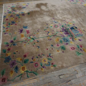 A lush tan rug displaying a bright, multicolored floral and vine design over gray wooden flooring.