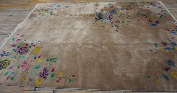 Low-pile beige rug with bright pink, purple, and green floral motifs on a distressed wood floor.