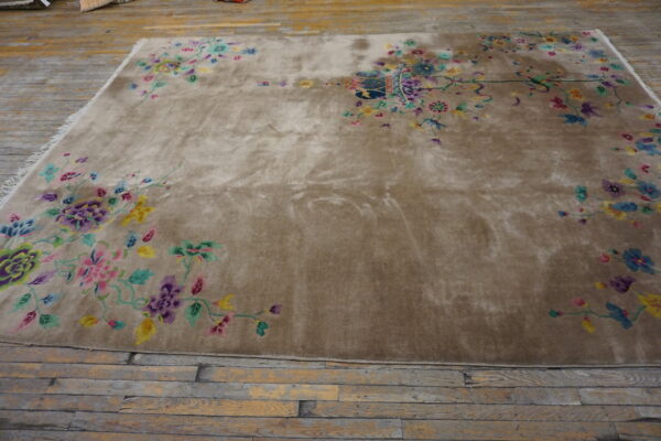 Shimmering taupe rug with bright floral vine borders lies on rustic wooden flooring.