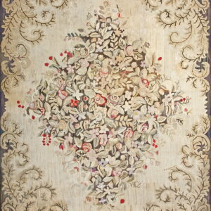 Textured rug in cream and muted colors, displaying a central floral bouquet and acanthus leaf border.