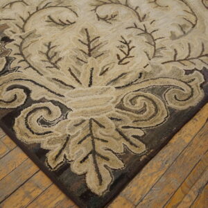 Beige and dark brown traditional foliate rug with textured looped pile on worn wood flooring.